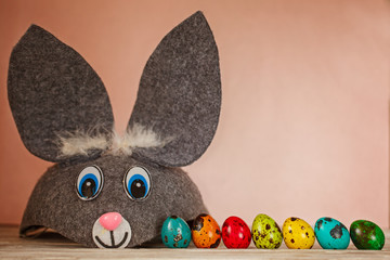 Funny bunny and colored quail eggs on pink background. Easter Spring holiday concept