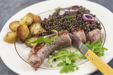 France Grilled Toulouse sausage with roasted potatoaes and salad and lentils on white background