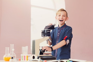 Schoolboy looking in microscope on lesson