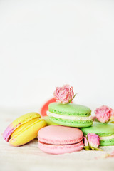 Dessert: A Delicate Fresh Colorful French Macaroons In Pastel Colors With Flowers Roses On A Light Textile Background, Top View