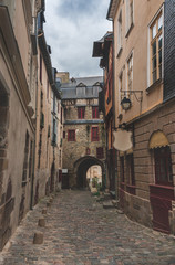 Narrow winding ancient street with cobblestone road and historic houses in old town in Rennes, Brittany, France
