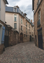 Narrow ancient street with cobblestone road and historic houses in old town in Rennes, Brittany, France