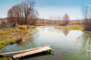 spring landscape, river with a wooden bridge,  fine day