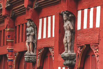 Historic red half-timbered house with wooden statues on facade in old town in Rennes, Brittany, France