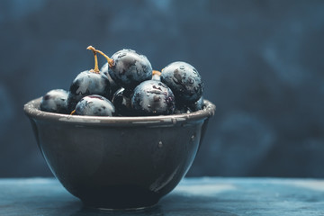Close-up of the wet fresh blue grape in a black bowl. Mystic light food photography style.