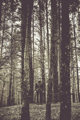 Fototapeta premium A lonely guy in a pine forest in the autumn time. Monochrome photo