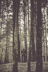 A lonely guy in a pine forest in the autumn time. Monochrome photo