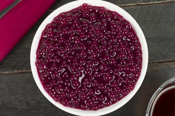 Brazilian dessert called sagu in wine version in a bowl in black wood background seen from above