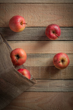 Top view image with red apples and canvas bag on the raw wooden background.