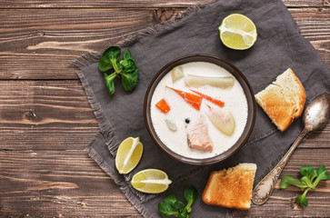 Scandinavian fish creamy soup with salmon on a wooden background. Top view, copy space.