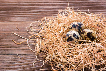 Quail eggs on a pile of straw on a wooden table
