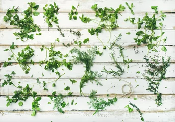 Flaches Muster aus Bündeln frischer grüner Kräuter. Petersilie, Minze, Dill, Koriander, Rosmarin, Thymian auf weißem Holzhintergrund, Draufsicht. Frühling oder Sommer gesundes veganes Kochkonzept oder Tapete © sonyakamoz