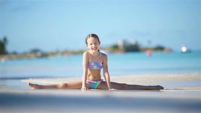 Adorable active little girl sitting on sandy beach