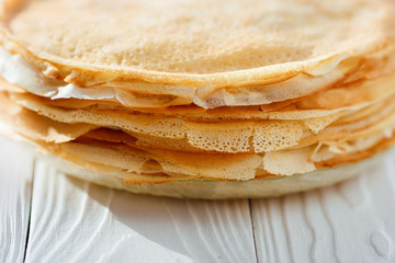 A stack of pancakes - Russian traditional dish. Thin delicious pancakes in a plate on a white background