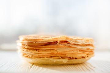 A stack of pancakes - Russian traditional dish. Thin delicious pancakes in a plate on a white background