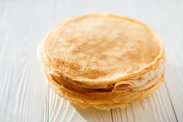 A stack of pancakes - Russian traditional dish. Thin delicious pancakes in a plate on a white...