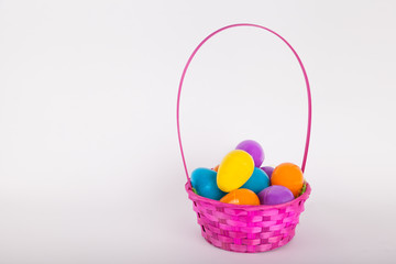 Easter egg basket with brightly colored plastic easter eggs on white background 