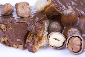 hazelnuts and bun with chocolate cream on white background