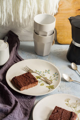 Millet brownie. White plates, cups of coffee and black esspreso maker. White and light blue background. Woolen tapestry.