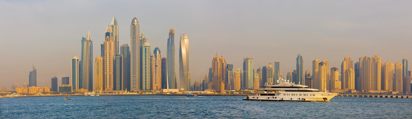 Fototapeta na wymiar Dubai - The evening panorama of Marina towers from the Palm Island wth the luxury yacht.