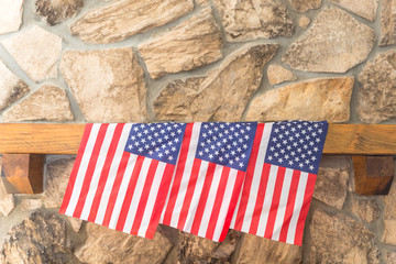 Three American flags on a stone fireplace mantle