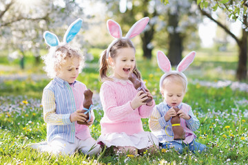 Garden Easter egg hunt. Kids eat bunny chocolate.