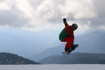 snowboarder jumps into the clouds and mountains