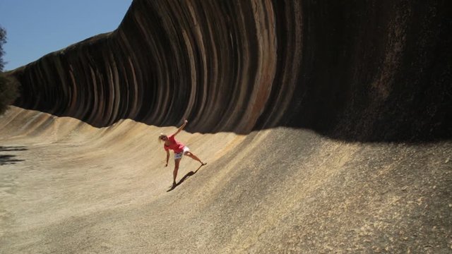 Australian outback freedom concept. Happy Caucasian woman surfer at Wave Rock in Hyden, Western Australia. Female a natural ocean wave shaped rock in Hyden Wildlife Park.