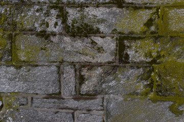 Irregular cobblestone wall with moss and grime closeup texture background