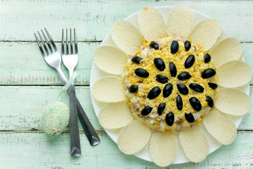 Sunflower salad decorated with potato chips, corn, egg and olive