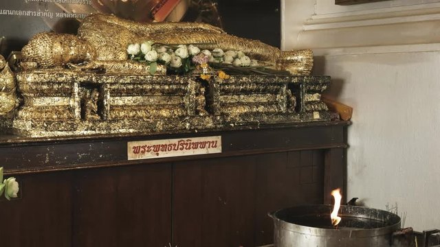 a prostrate buddha statue and a flame for lighting incense at phu khao thong, golden mount temple, in bangkok, thailand