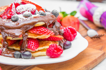 dish with pancakes and strawberry,raspberry and blueberry and chocolate