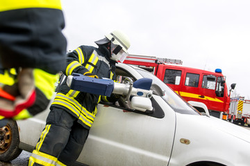 Feuerwehrm&auml;nner schneiden mit einer Rettungsschere ein Fahrzeug auf