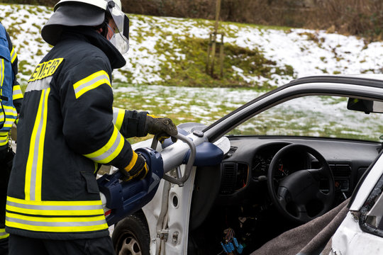 Feuerwehrmänner schneiden mit einer Rettungsschere ein Fahrzeug auf
