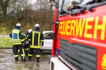Feuerwehrmänner befreien ein Unfallopfer nach einem Verkehrsunfall aus einem kaputten Auto