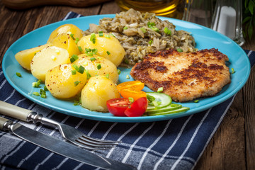 Fried pork chop, baked potatoes and fried young cabbage.