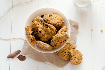 Homemade oatmeal cookies with raisins and prunes with jug and glass of milk on white wooden background. No sugar, no flour, no fast carbs. 