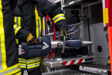 Feuerwehrmänner schneiden mit einer Rettungsschere ein Fahrzeug auf