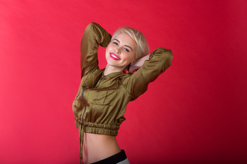 beautiful young girl with a smile and with a short hairdo in a jacket on a red background