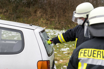 Ein Feuerwehrmann zerstößt eine Scheibe von einem Fahrzeug