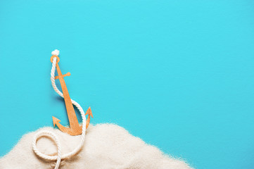 Blue background with handmade paper anchor on the sand