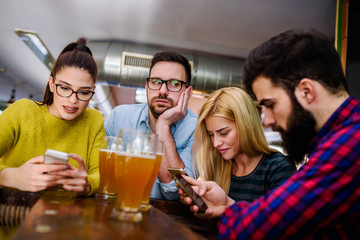 Man is getting bored in the bar while others using their smartphones