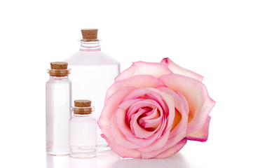 Fototapeta na wymiar Pink rose and three glass bottles with transparent liquid