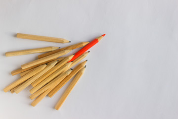 Red pencil standing out from crowd of plenty identical  pencils on table. Leadership, uniqueness, independence, initiative, strategy, dissent, think different, business success concept.