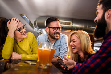 Friends in pub having fun drinking, laughing
