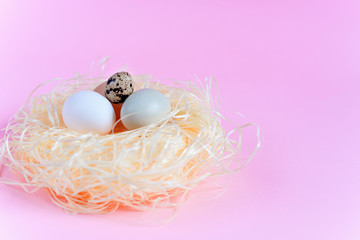 Easter eggs of different colors in a straw nest on a pink background, Top view free copy space. Flat lay. Easter concept.