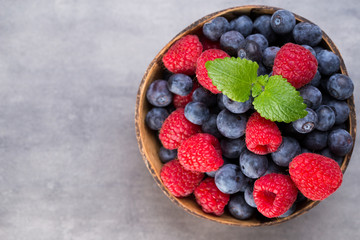 Juicy and fresh blueberries with green mint on rustic gray table.