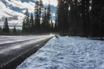 Snow on the side of a road with mist in the background.