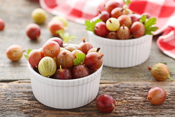 Ripe gooseberries fruit in bowl on wooden table