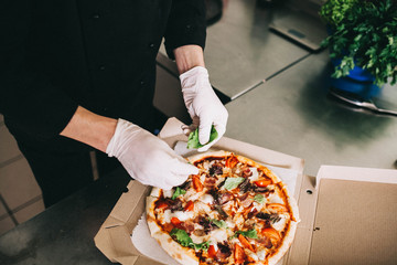 Man's hands cut ready pizza in a cardboard box - 193348000